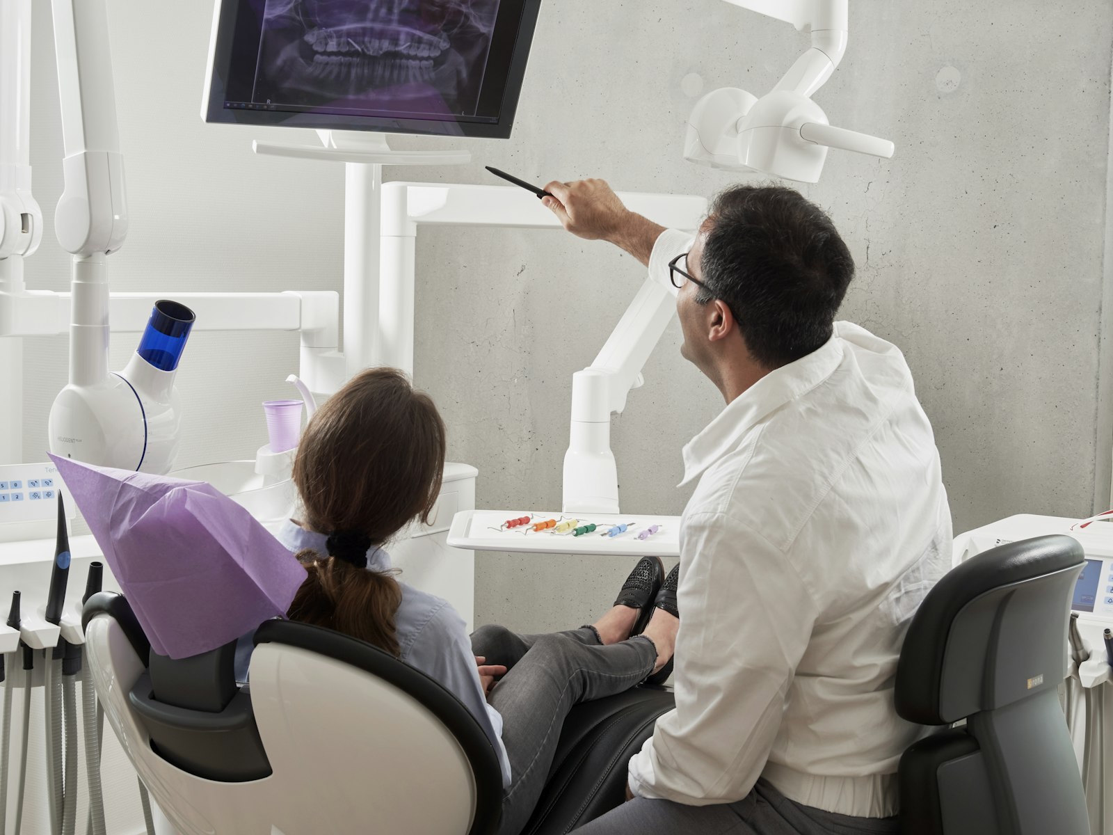 A dentist showing a patient their digital panoramic X-ray on a chairside screen